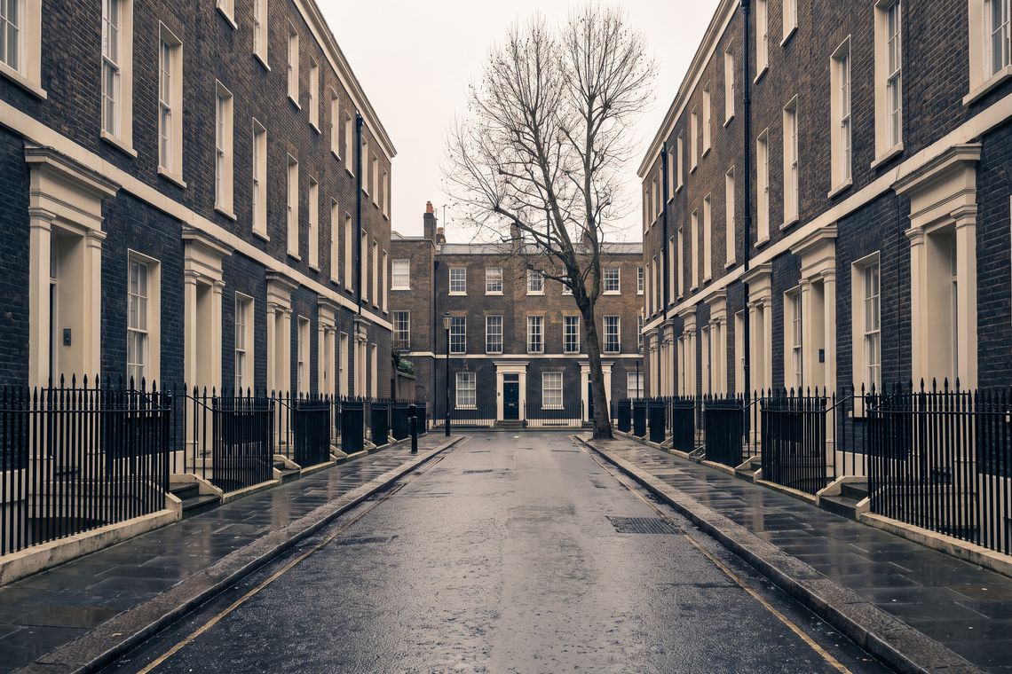 A quiet Georgian terrace in central London on an overcast morning, the road empty after rain.